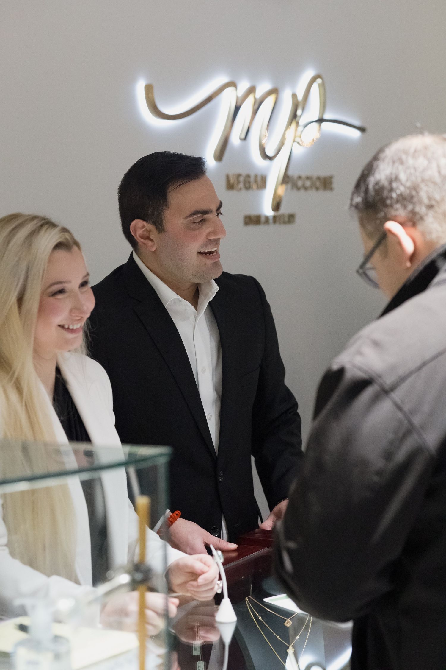 Business conversation taking place at jewelry counter under illuminated MP store sign.