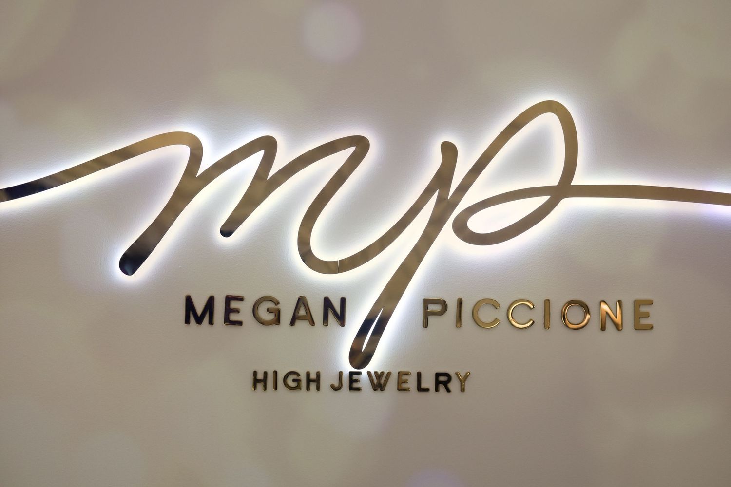 Illuminated 'MP High Jewelry' logo sign with elegant cursive lettering.