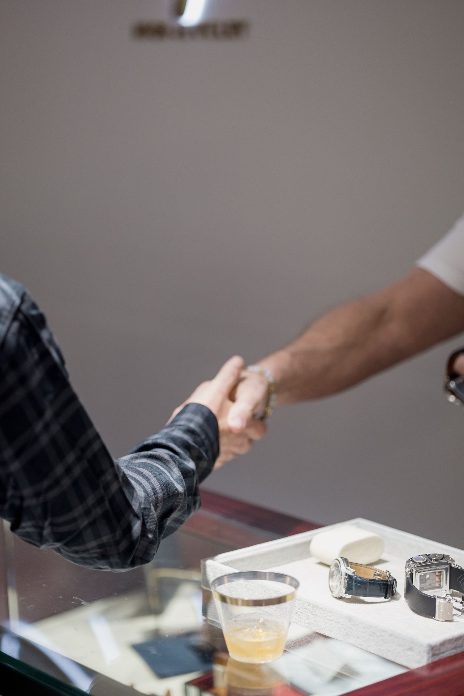 Professional business handshake over a desk with drinks and papers in the background.