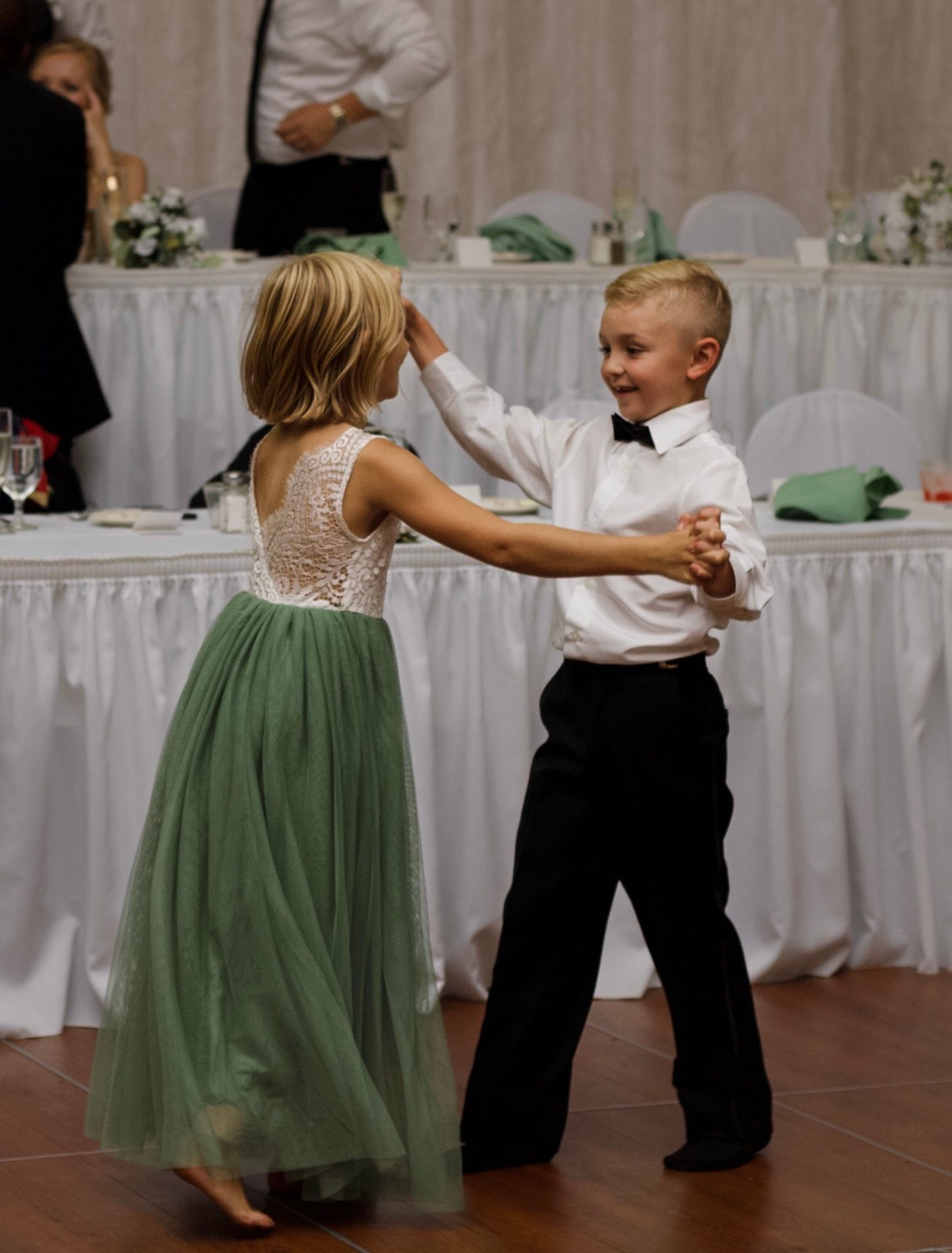 Children in formal wear dancing together at wedding reception.