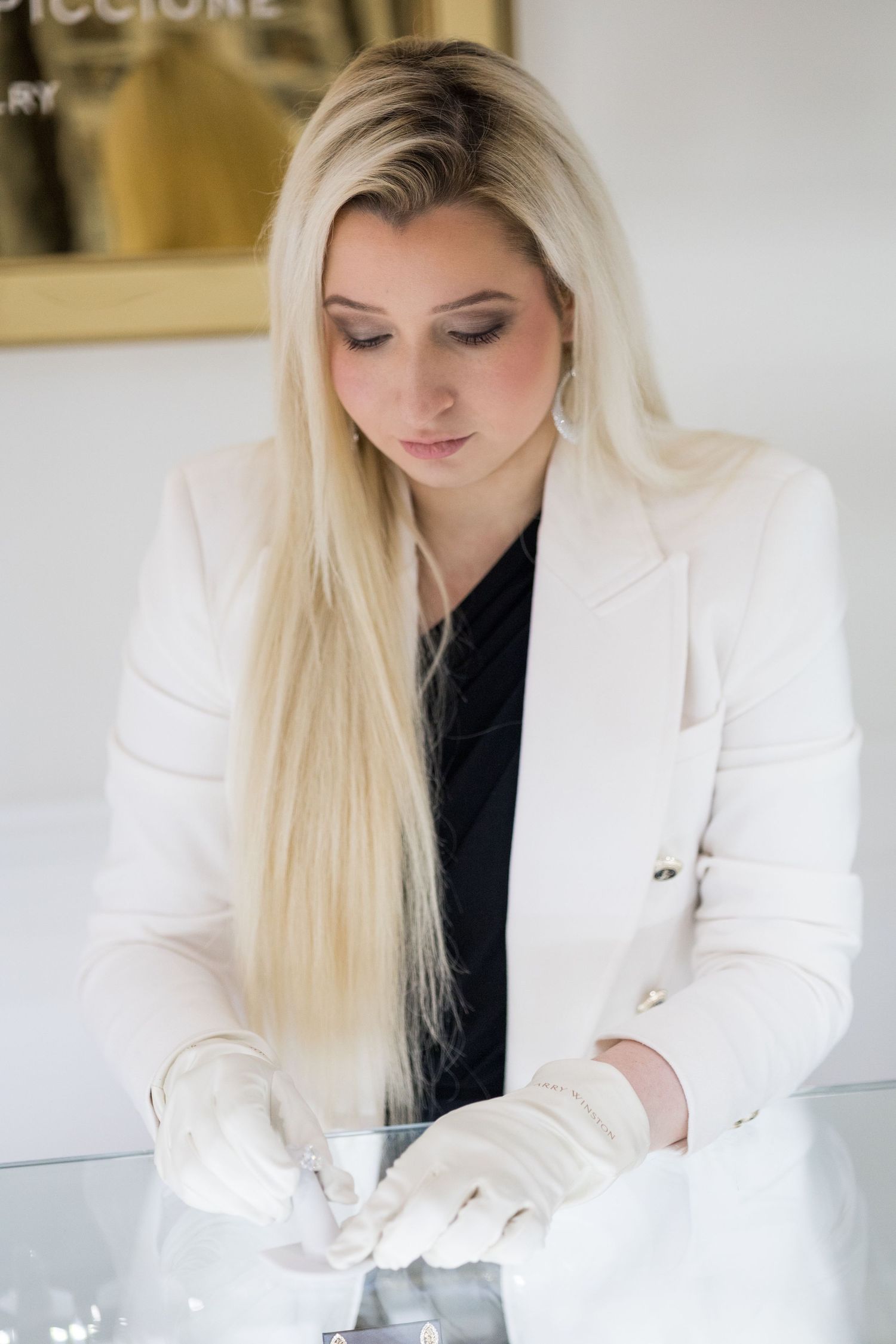 Professional jewelry handling with white gloves in pristine retail environment.