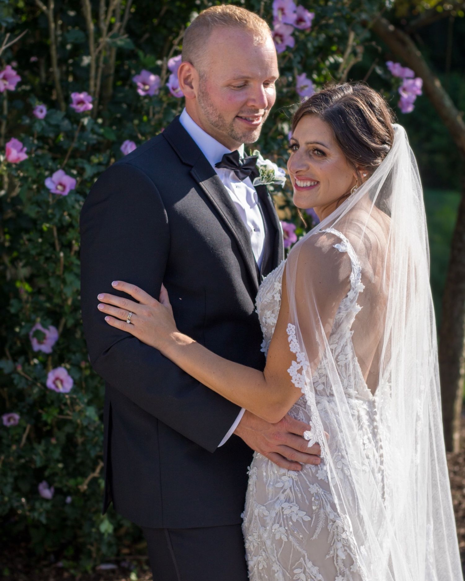 Wedding portrait of couple embracing near blooming rose garden.