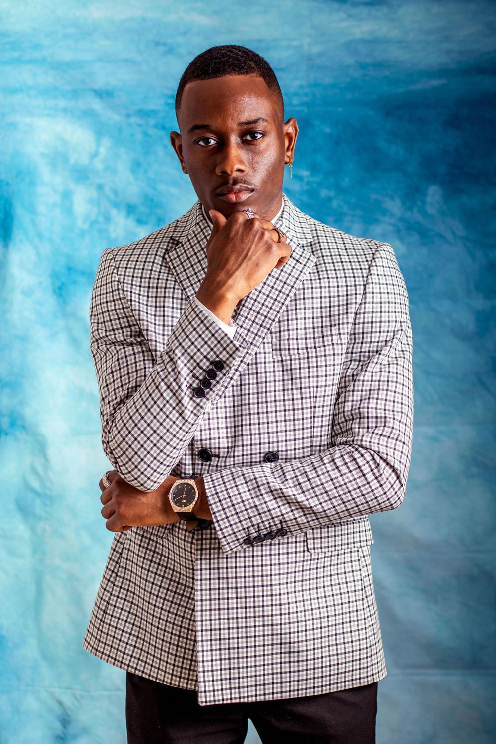 Professional headshots against blue backdrop featuring checkered blazer and thoughtful poses.