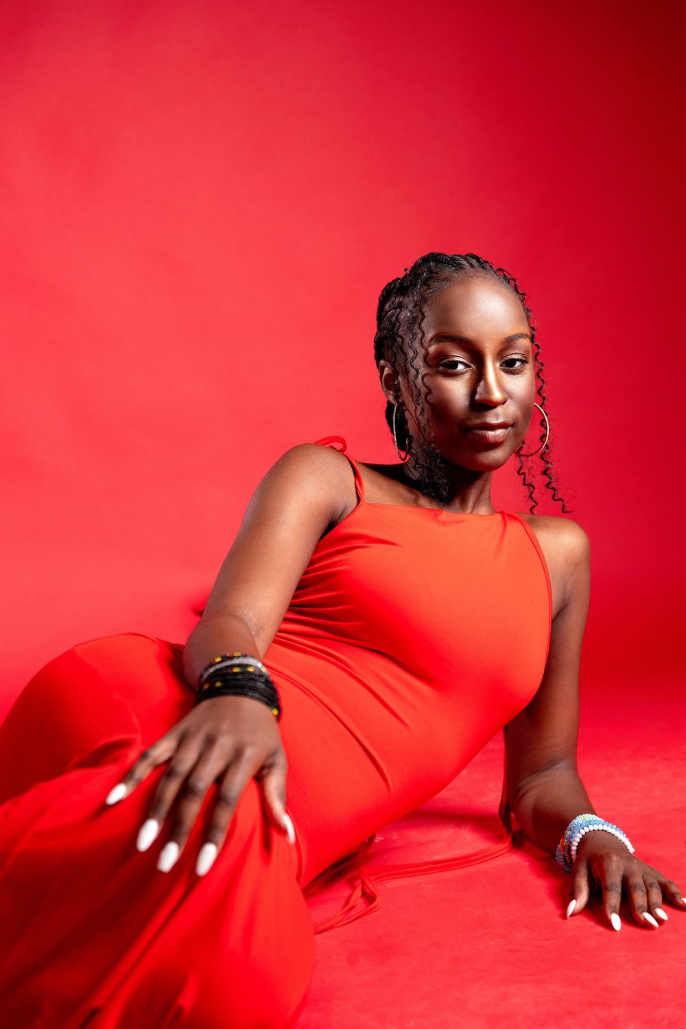 Professional portrait session featuring red dress against vibrant red backdrop in elegant poses.
