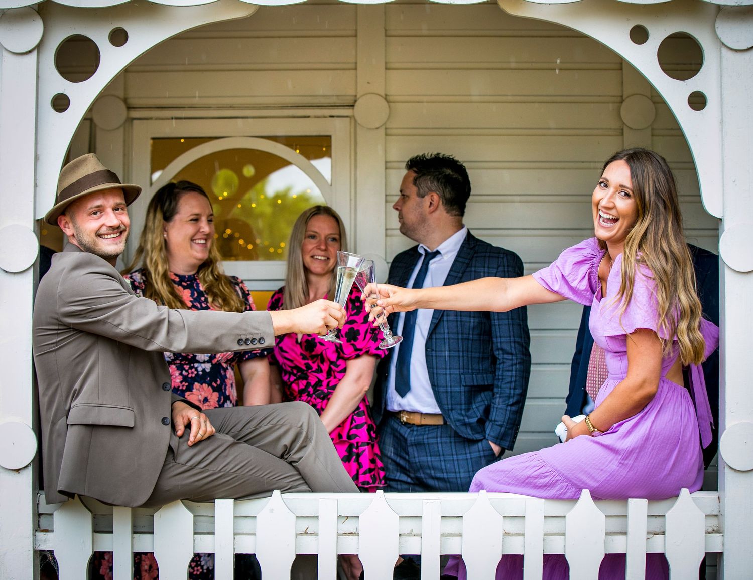 Wedding party having fun and posing on a decorative white gazebo.