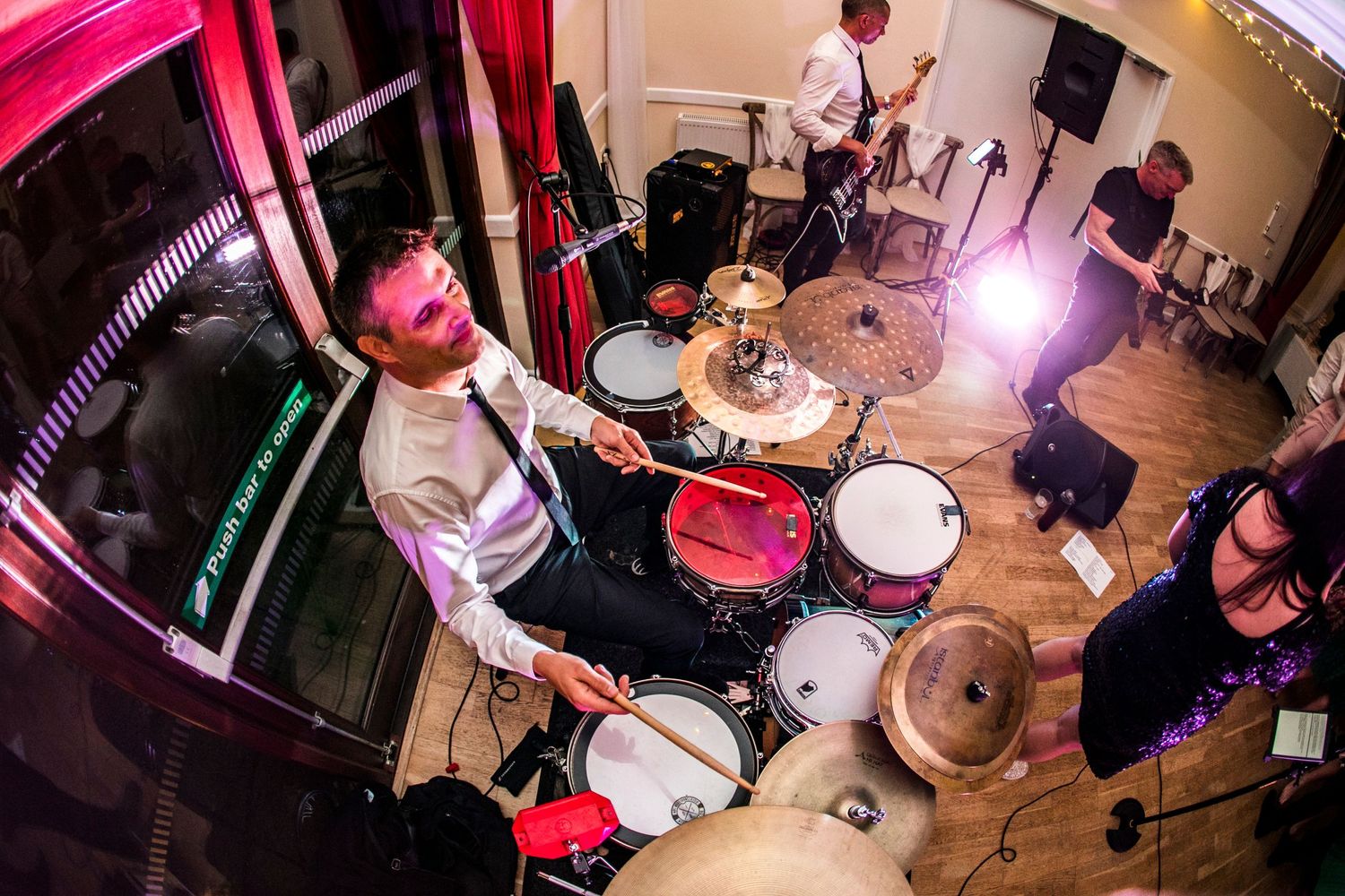 Musicians performing at an indoor event with colorful lighting effects.