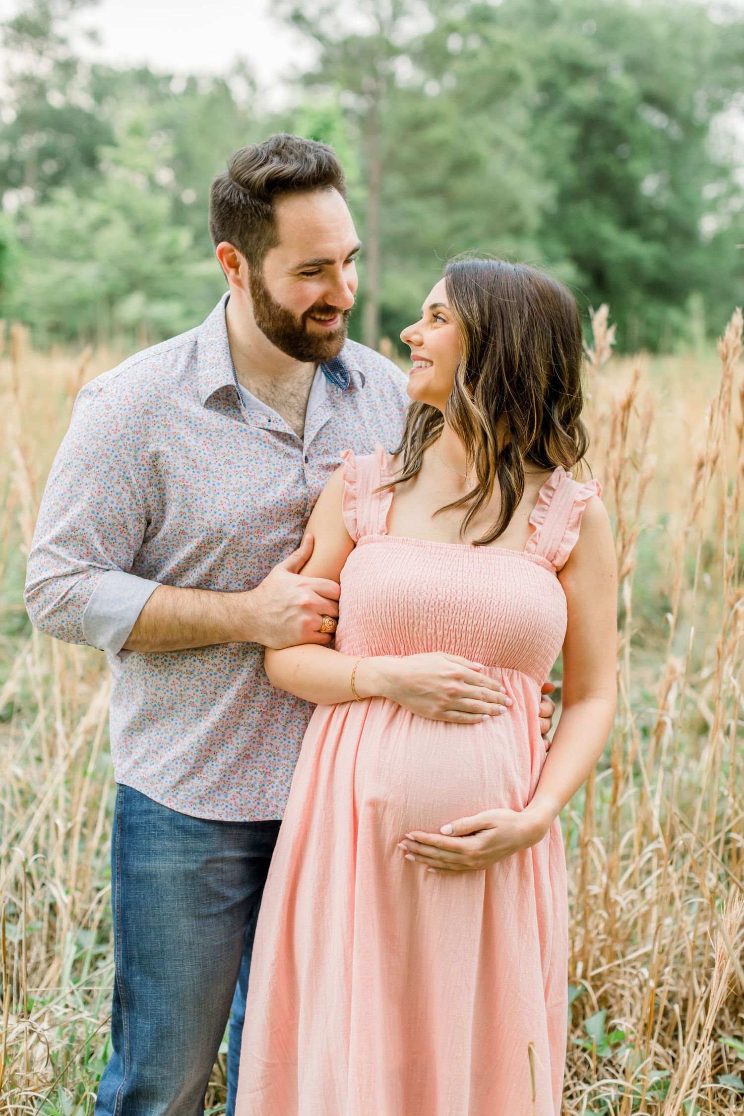 A joyful moment shared between a couple on a nature trail with golden grass and green trees.
