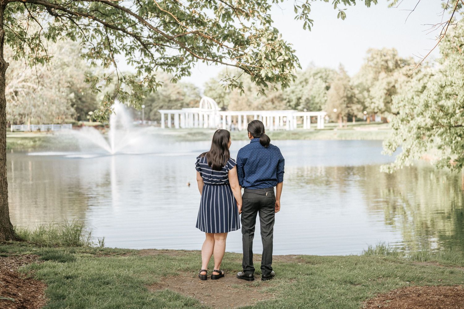 Scenic lakeside view with trees and a white gazebo in the background.
