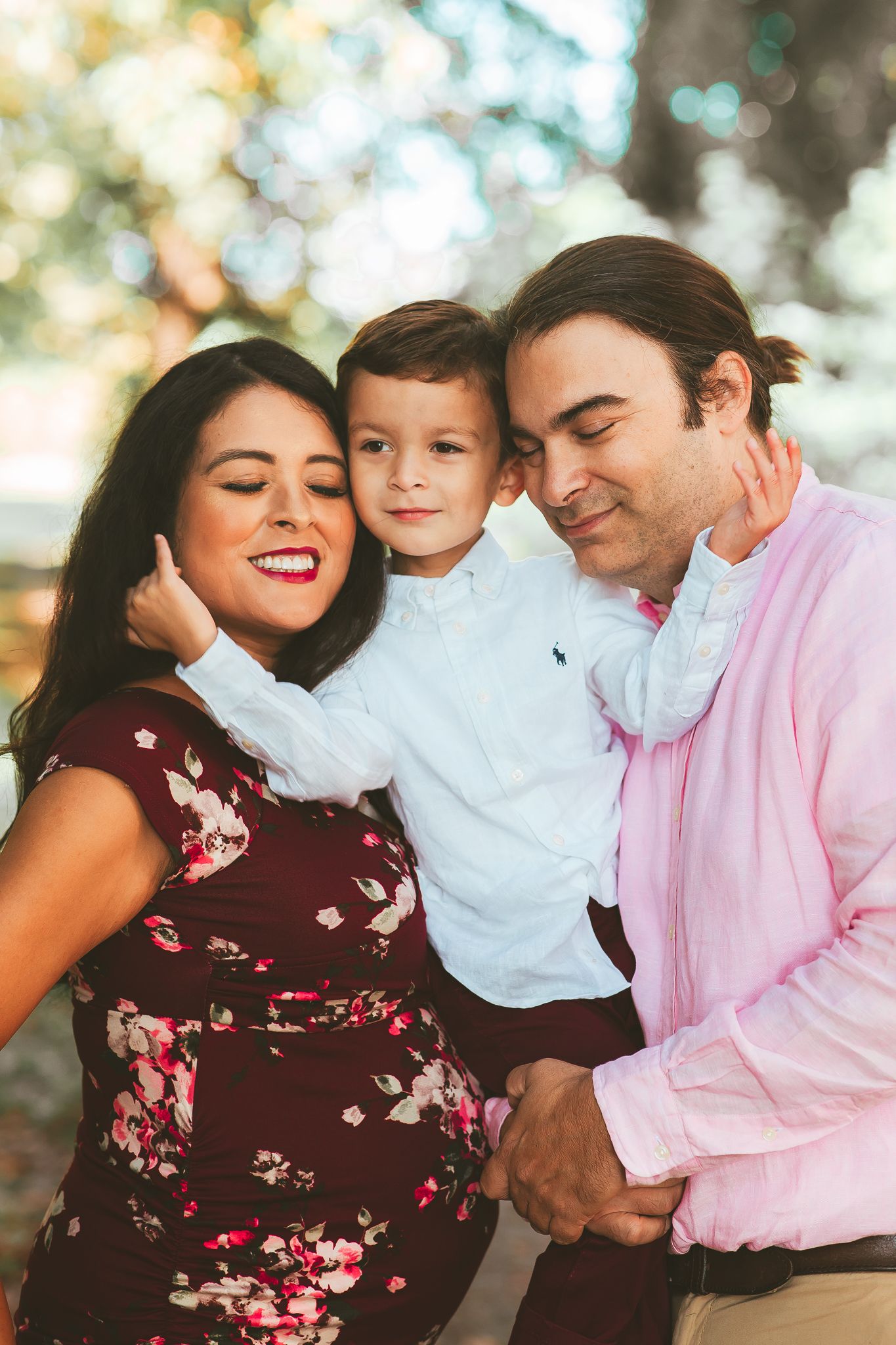 Family of three sharing joyful moment outdoors in casual attire.