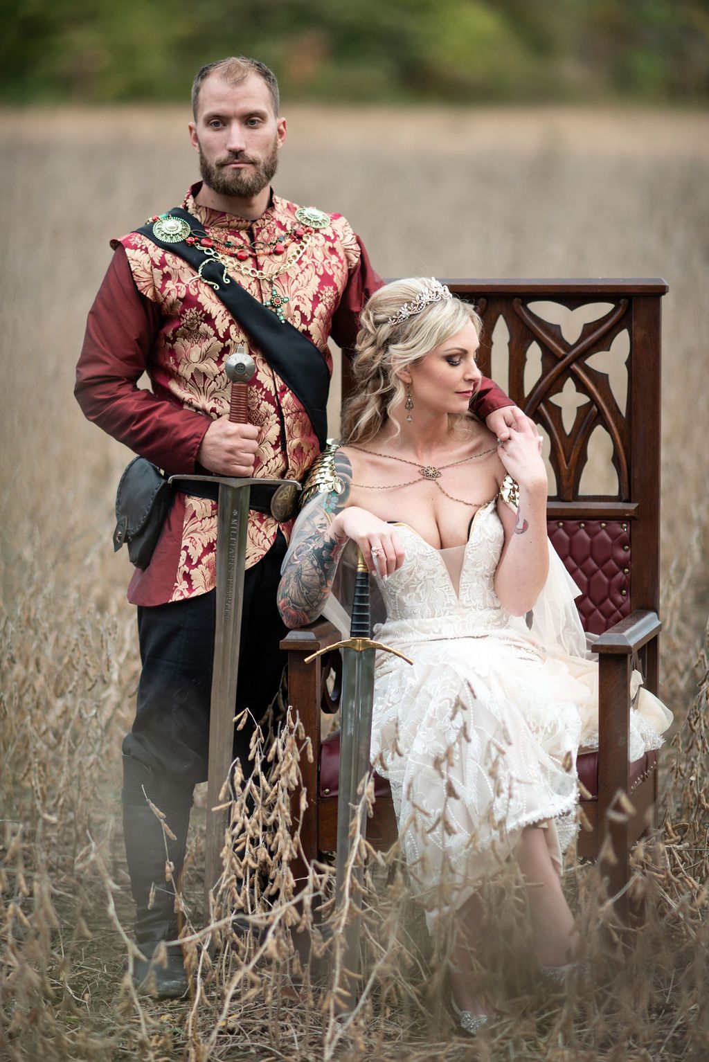Bride Sitting in a Chair With Groom Standing Next to Her. They Both Have Swords