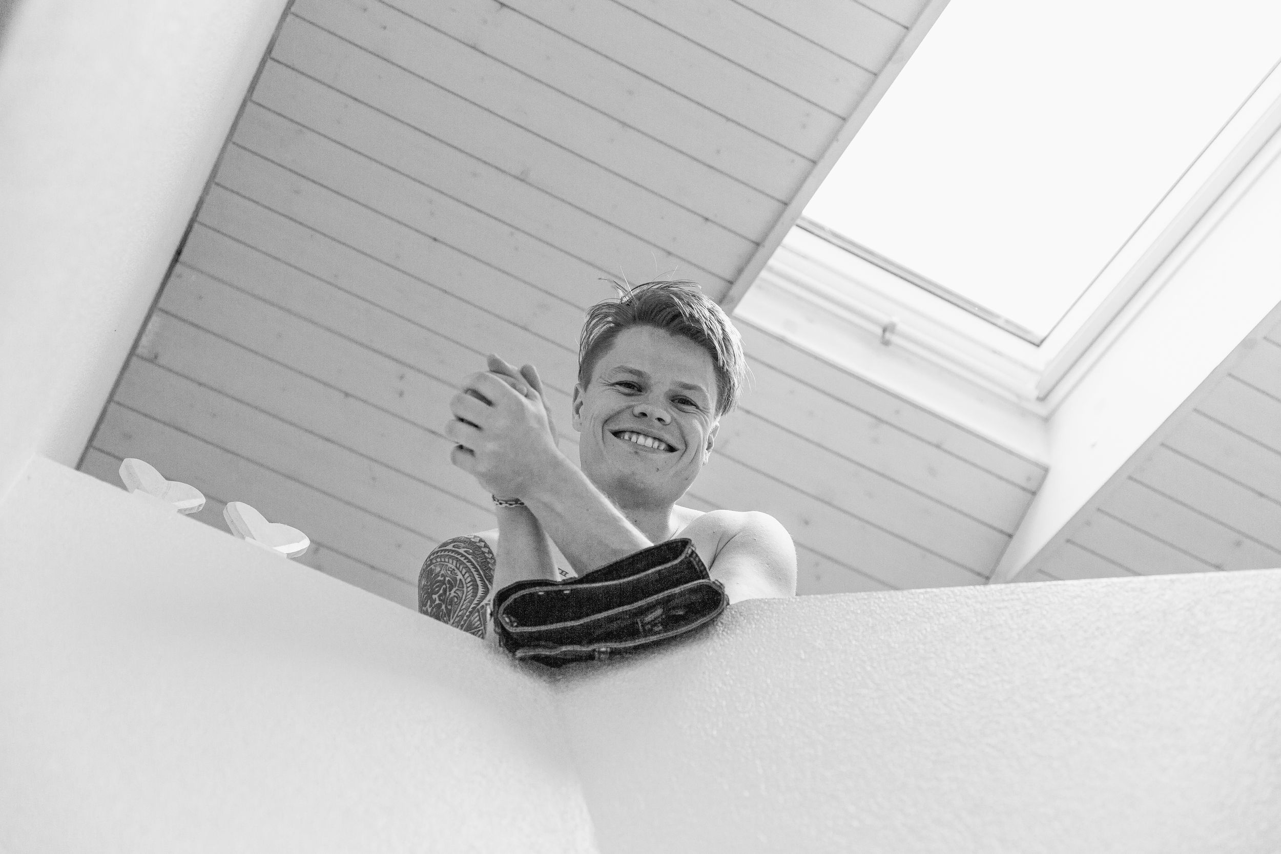 Candid portrait of a smiling groom sitting and relaxing during his wedding day preparations.