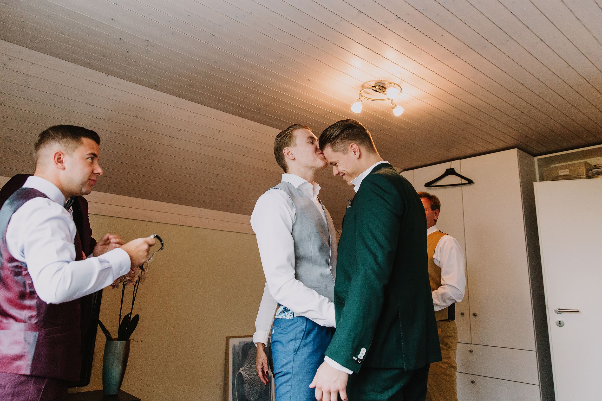 Groom sharing a quiet moment with his groomsmen while getting dressed for his Brunnen wedding.