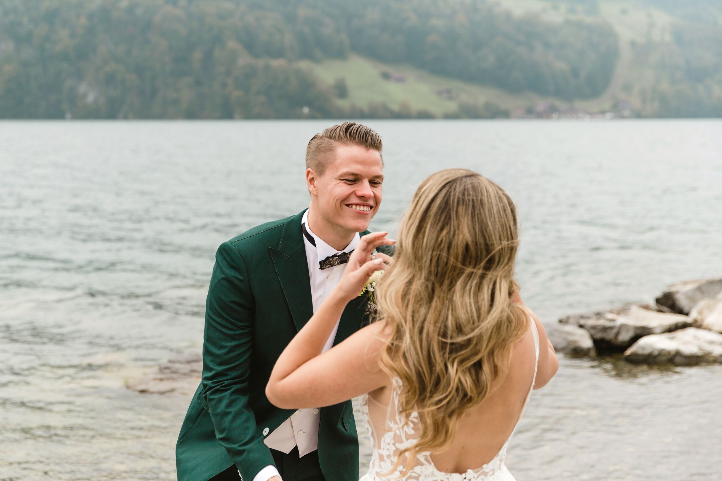 Candid portrait of a bride and groom laughing together during their outdoor wedding session by the lake.