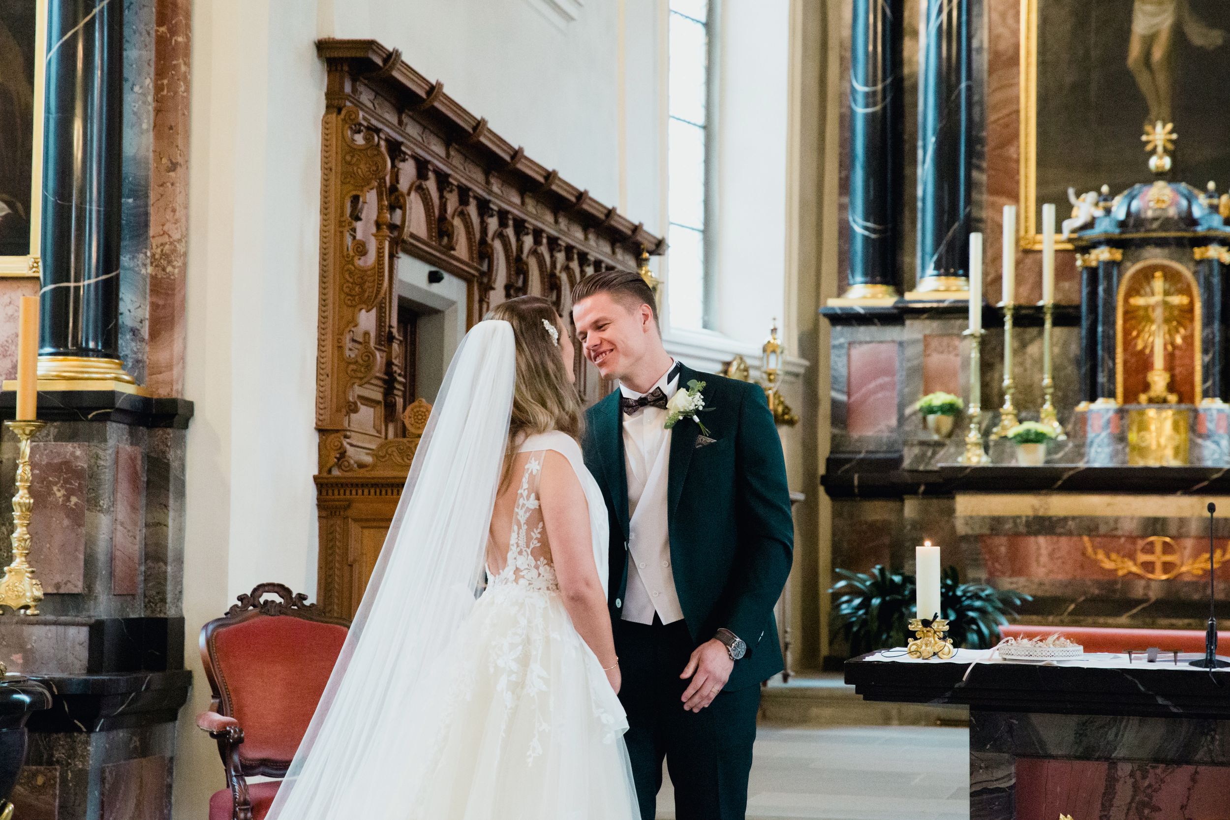 Bride and groom sharing a smile at the altar during their wedding ceremony in a historic church.