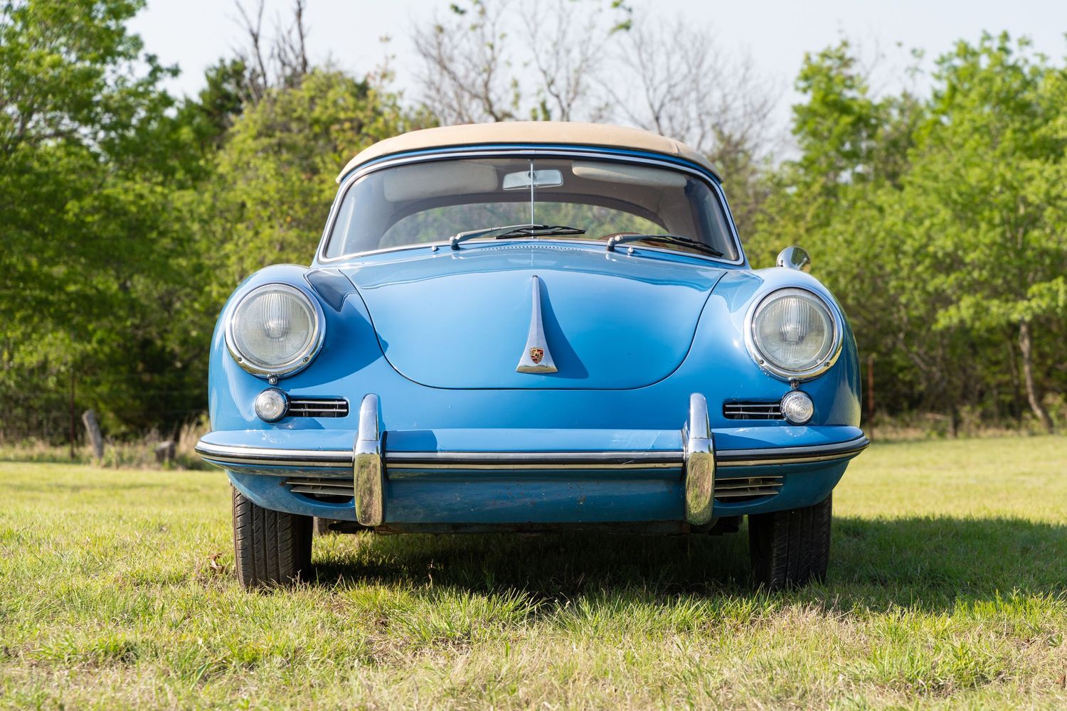 Front view of a classic blue Porsche 356 on grass with distinctive round headlights.