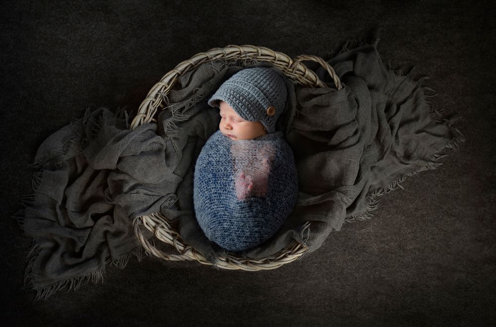 Expertly posed newborn in a heart-shaped prop for a luxury baby gallery.