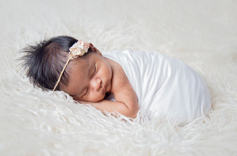 Expertly posed newborn in a heart-shaped prop for a luxury baby gallery.