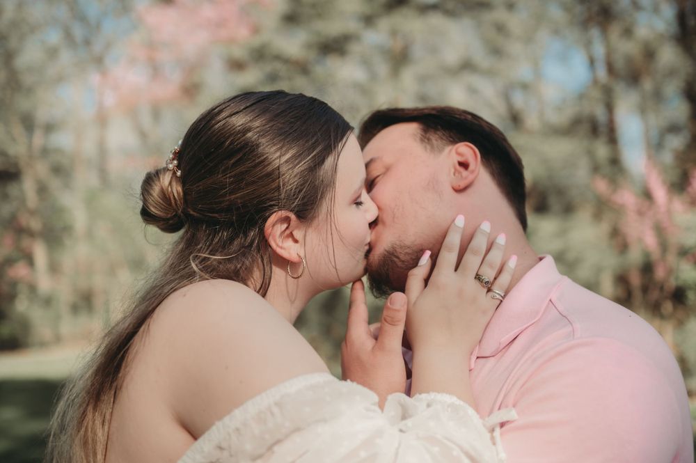 An intimate wedding moment captured in soft natural lighting with blurred foliage.