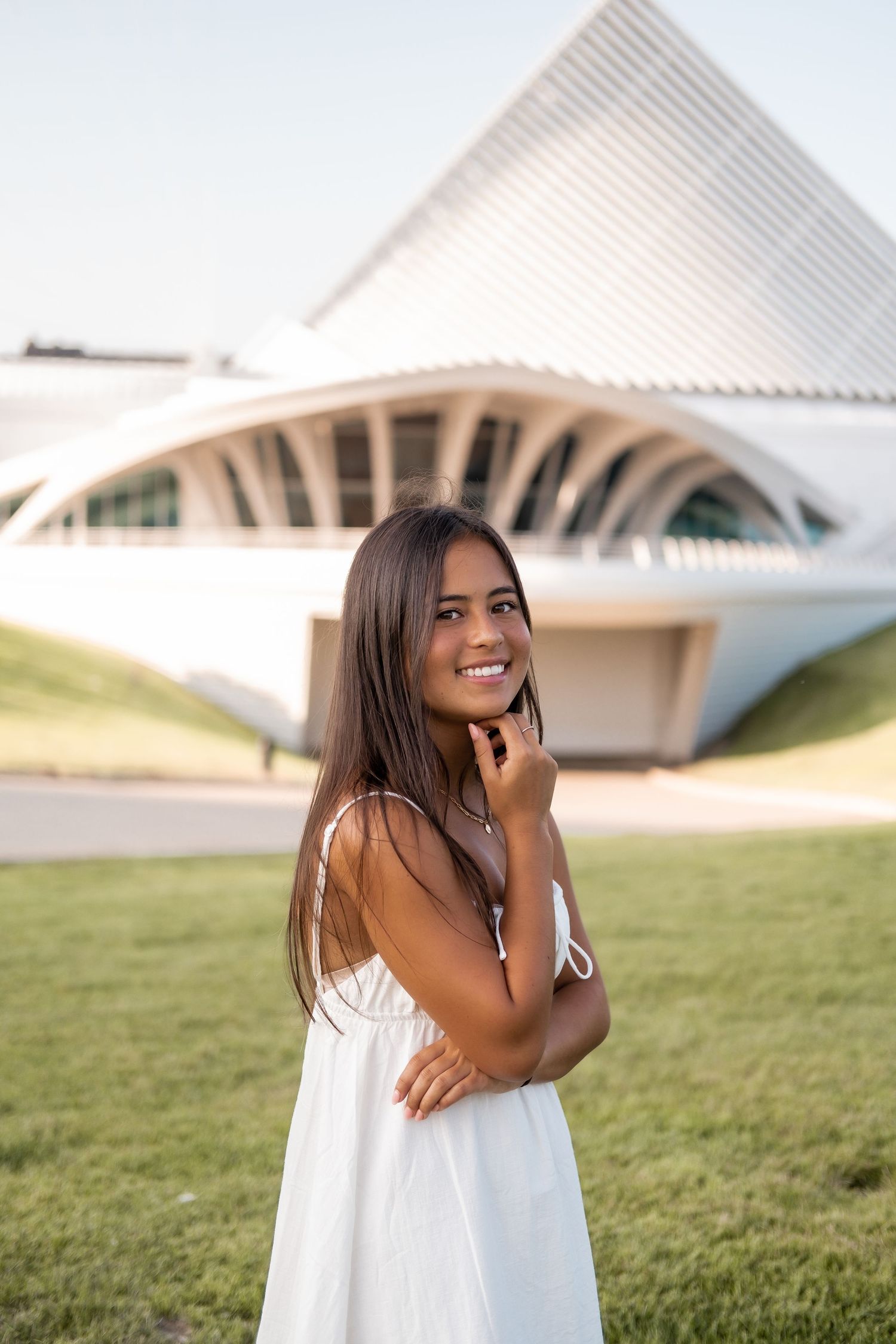 Modern white architectural building with geometric shapes surrounded by green grass on a sunny day.