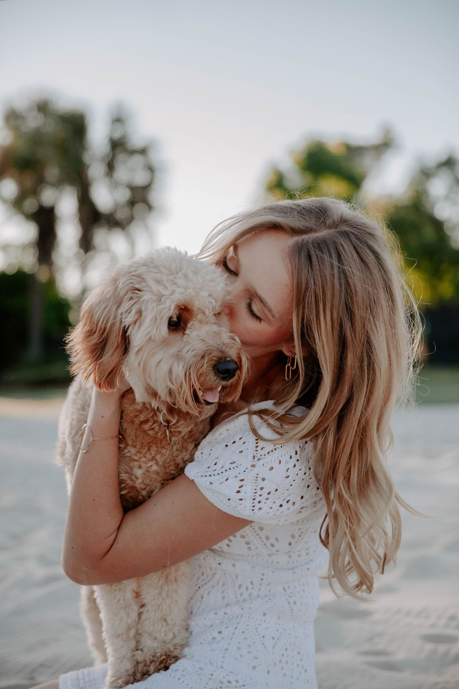 Senior photos of a blonde college graduate and student-athlete giving her dog a kiss.