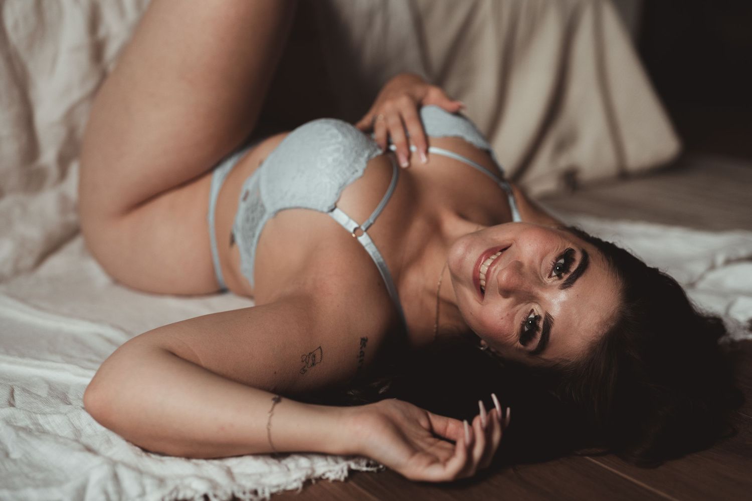 Femme cheveux noirs allongée tatouage sourire séance photo boudoir expérience Baudour Mons Belgique