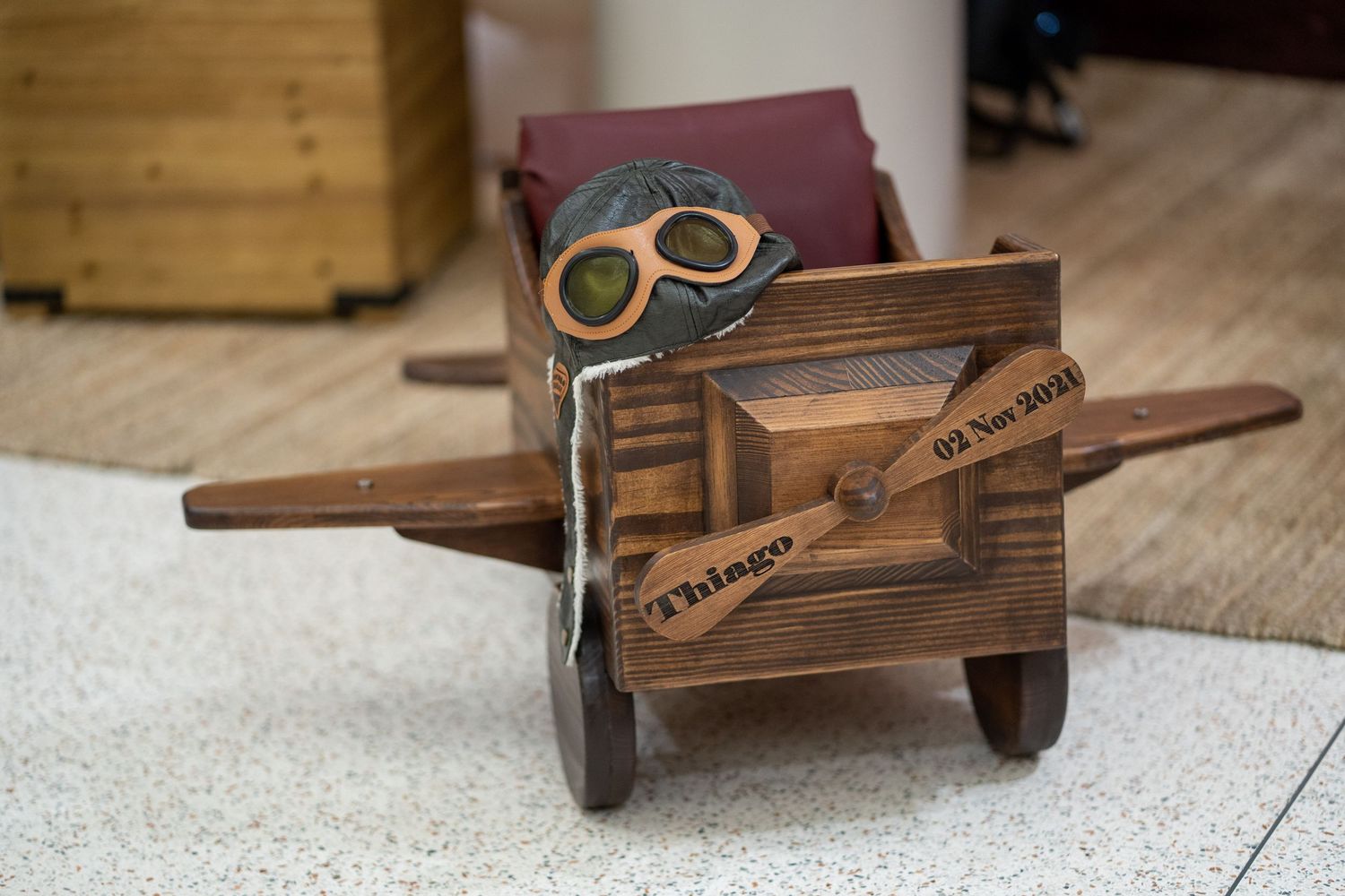 Vintage wooden toy wheelbarrow with goggles displayed on wooden floor.