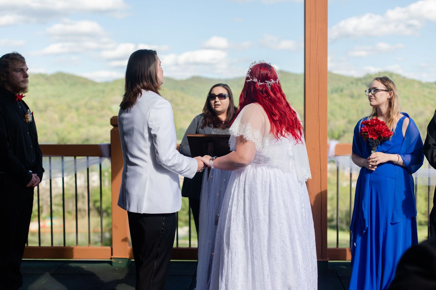 Wedding celebration on a covered deck overlooking scenic mountain landscape.