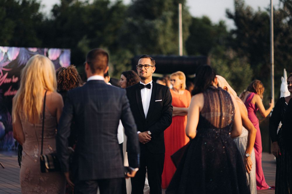 Formal wedding guests in elegant attire gather during outdoor evening event.