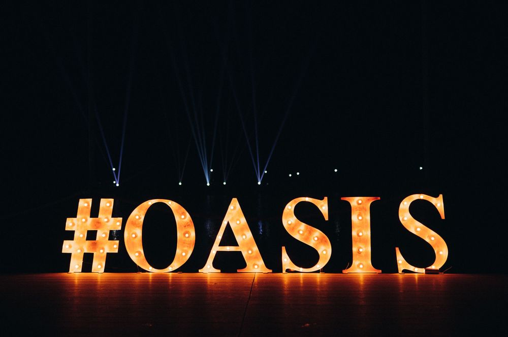 Illuminated #OASIS sign display with dramatic backlighting against dark background.