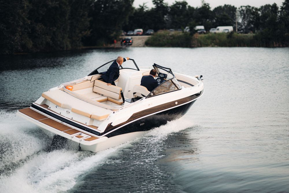Speedboat cruising across lake creating wake on calm water.
