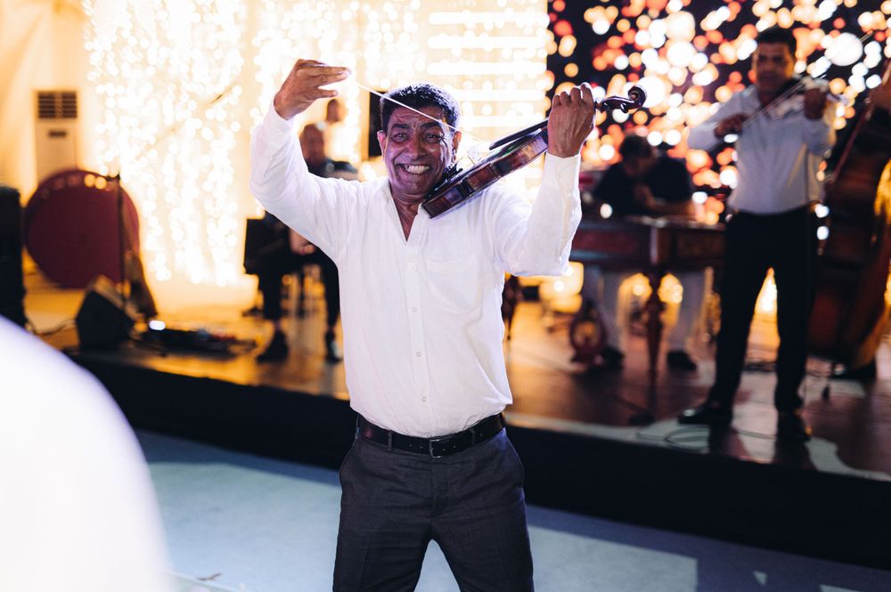 Person in white shirt celebrating enthusiastically on a dance floor with lights in background.