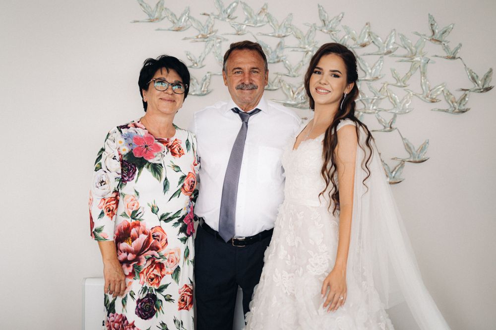 Family portrait against a white wall decorated with delicate paper cranes and floral accents.