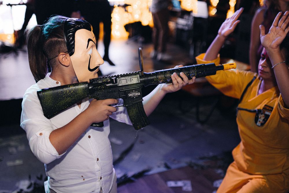 Person in white shirt holding toy gun prop at party event.