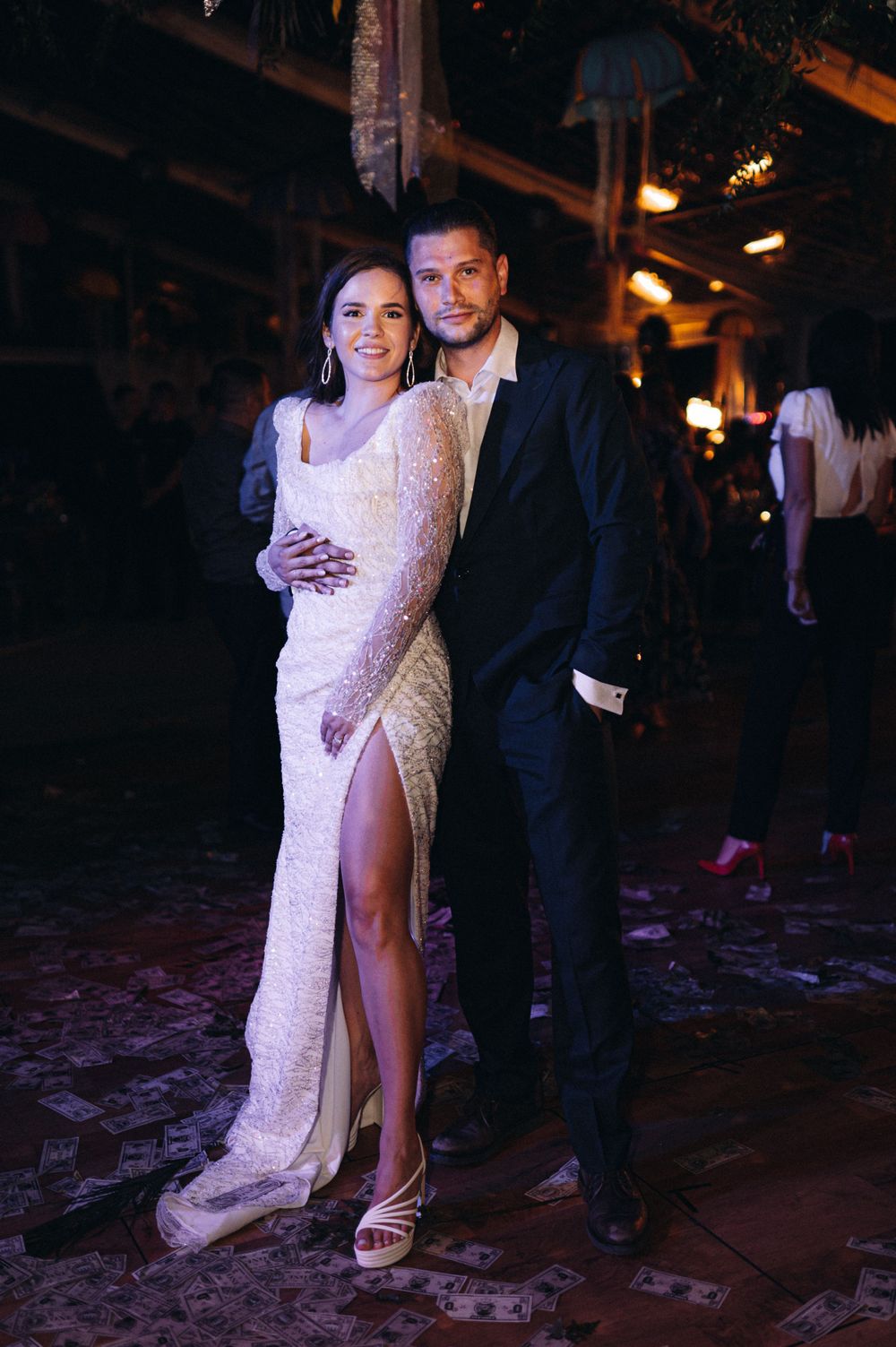 Couple posing in formal evening wear at glamorous indoor venue.