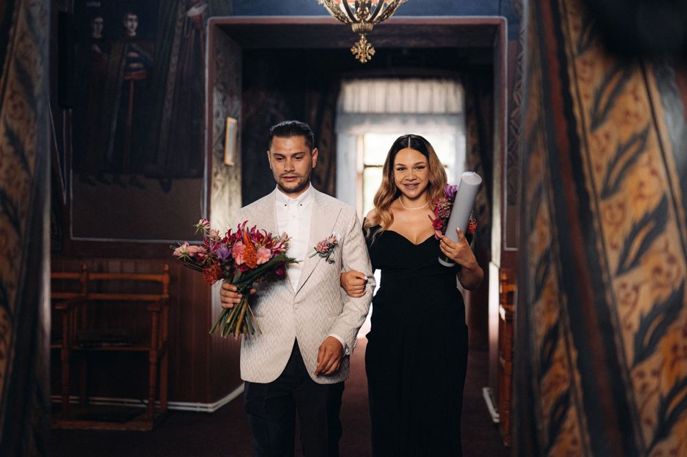 Couple walking through ornate vintage hallway during wedding celebration.