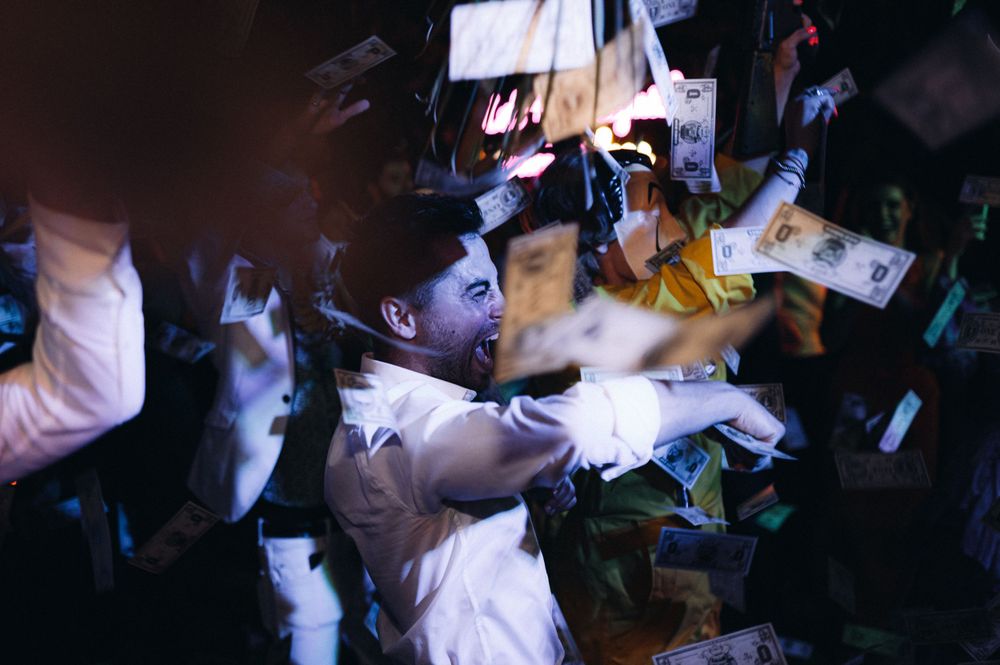 Celebration scene with money and lights flying through the air in a dark venue.