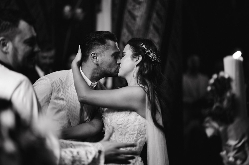 Black and white romantic moment captured during Orthodox wedding ceremony.