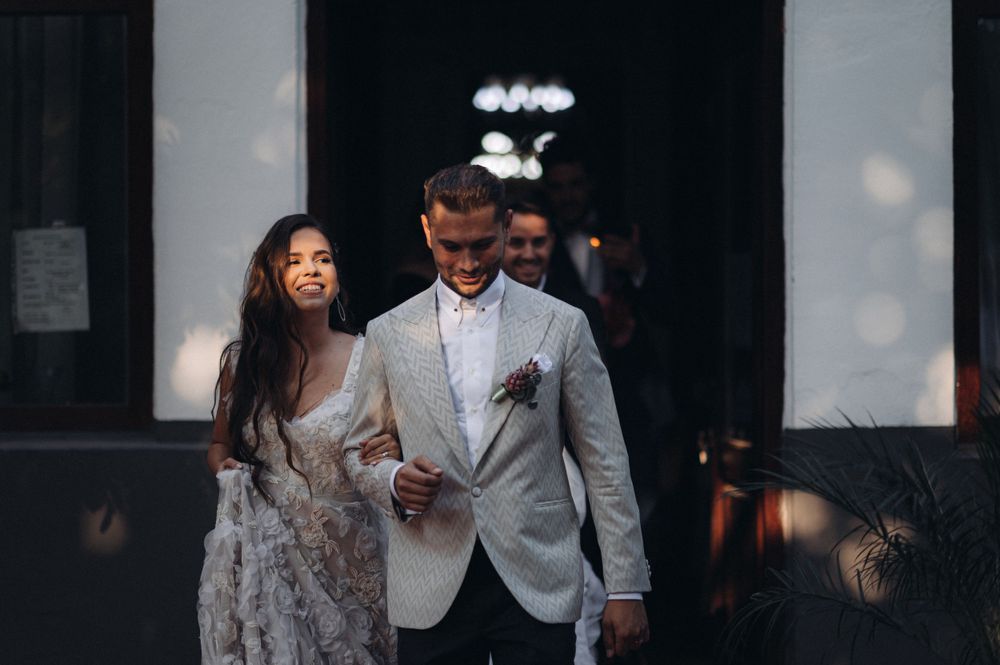 Couple walking together in formal wedding attire outside venue.