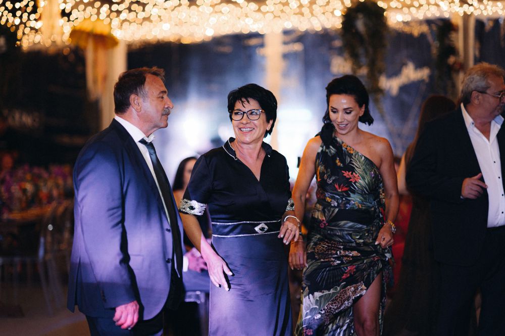 Three guests engage in animated conversation at an elegant evening celebration.