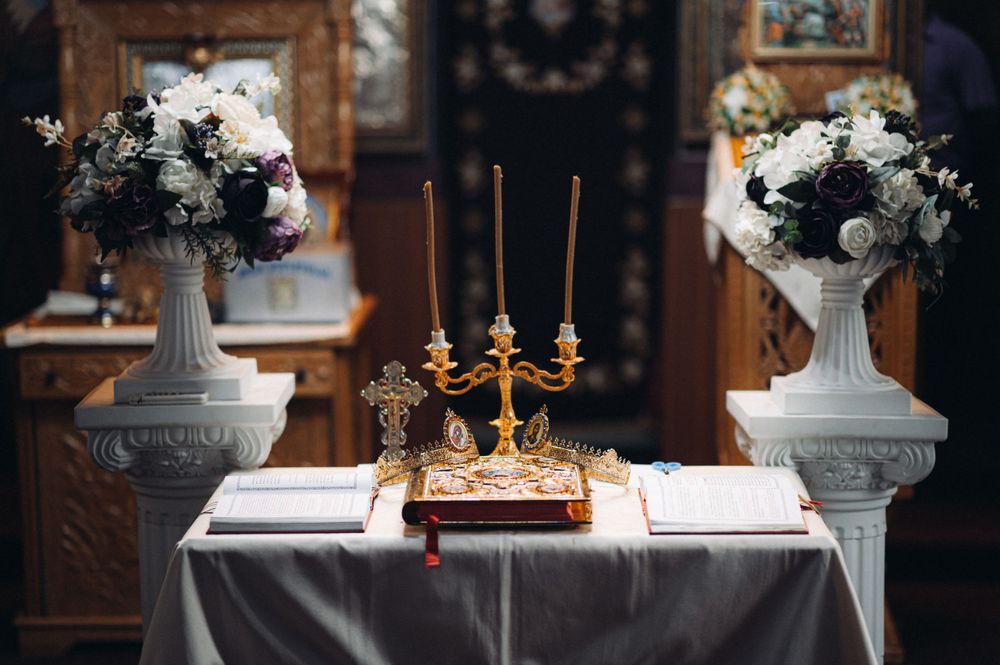Elegant church altar setup with white floral arrangements and golden candelabra.