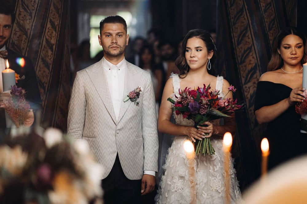 A couple during their wedding ceremony with the bride holding a vibrant purple bouquet.