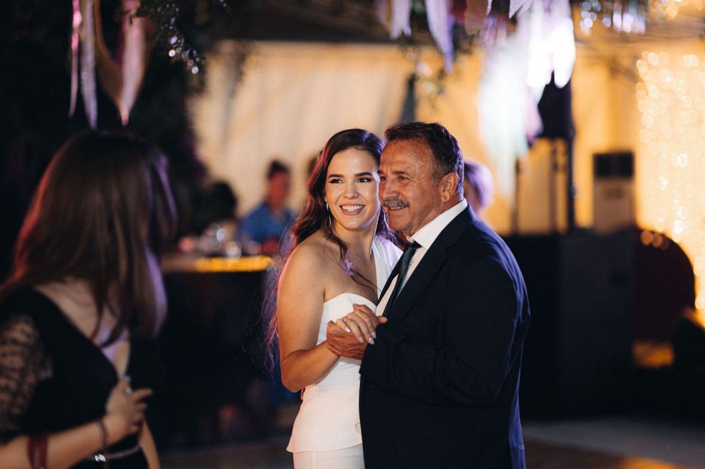 Couple shares intimate moment while dancing at festive celebration with twinkle lights.