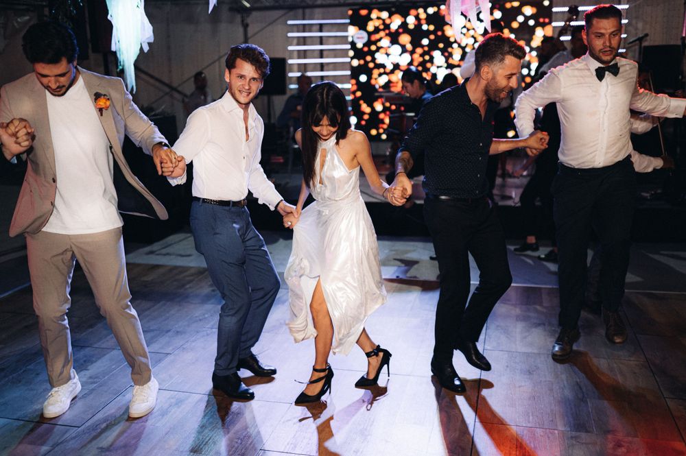Guests dancing energetically at a wedding reception with confetti falling from above.