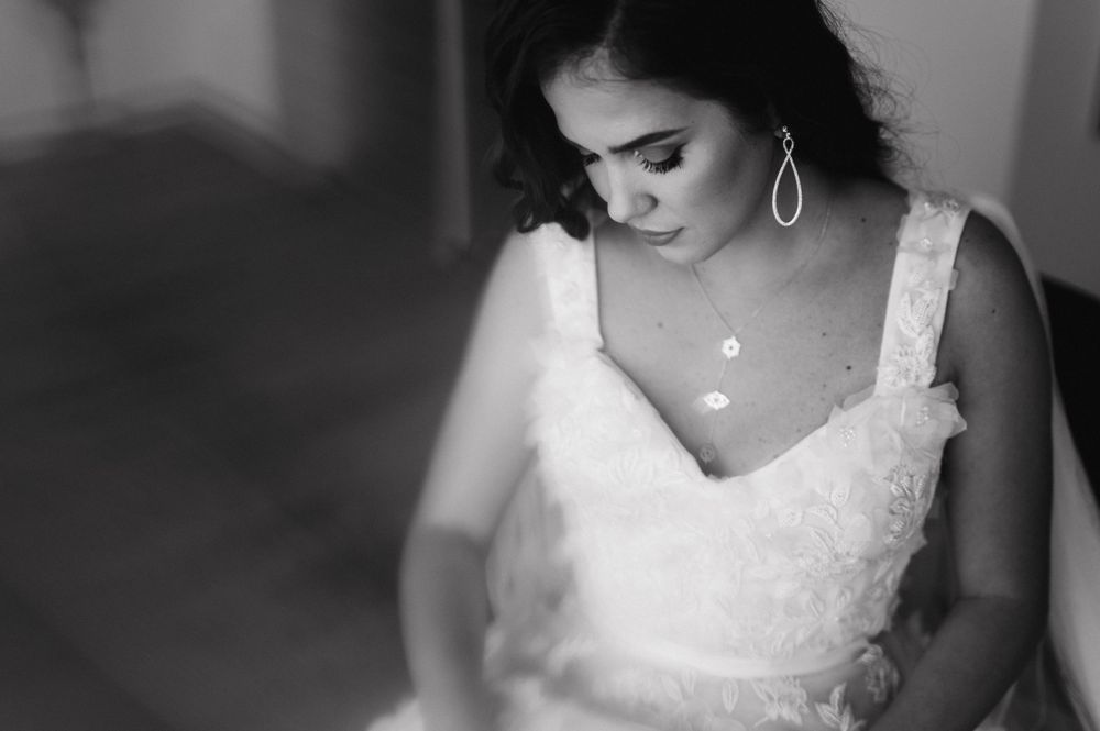 A black and white closeup of a bride in a lace wedding dress with delicate jewelry.