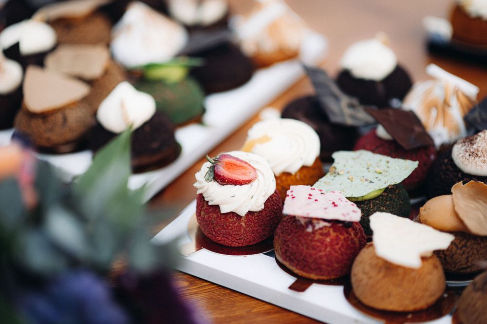 Assorted mini desserts and cupcakes beautifully displayed on dark serving platters.