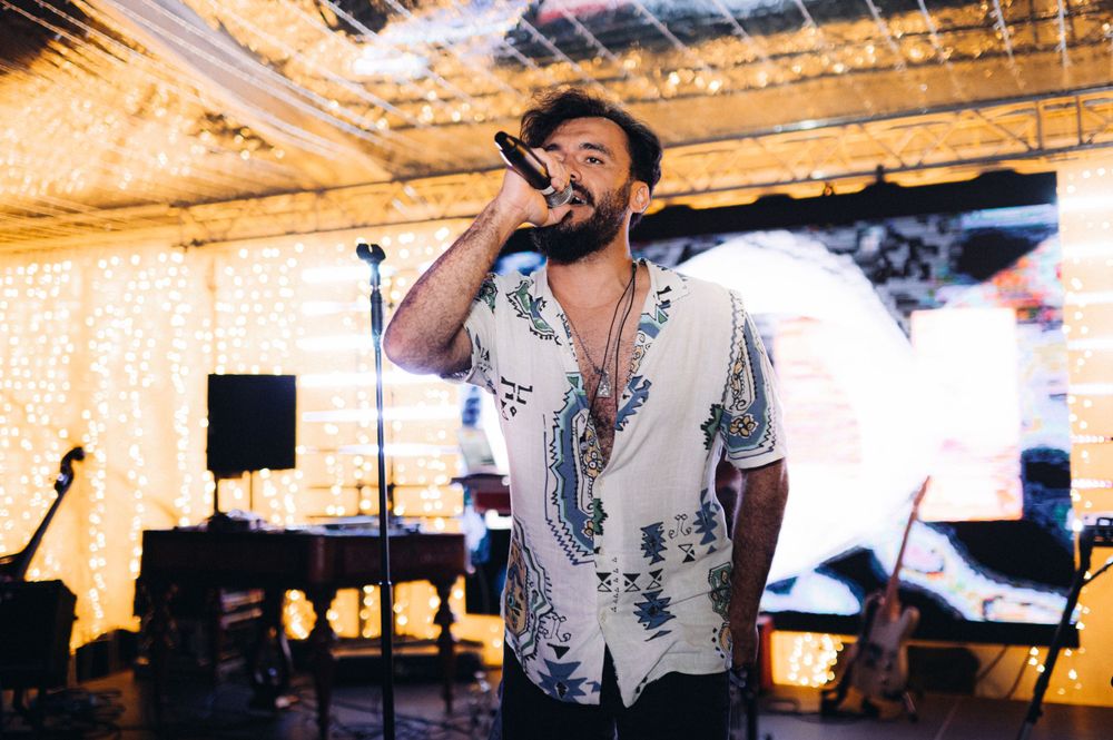 Performer singing into microphone on stage with dramatic lighting.