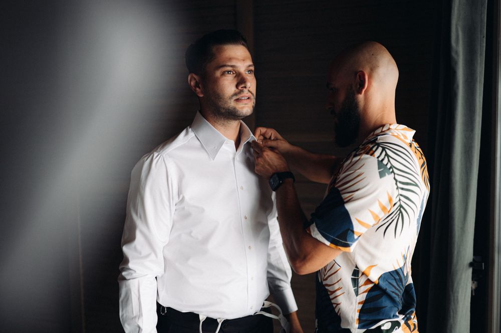 Two people preparing formal attire in a dimly lit room.