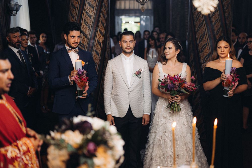 Wedding party standing at the altar with the couple in white and attendants holding candles.