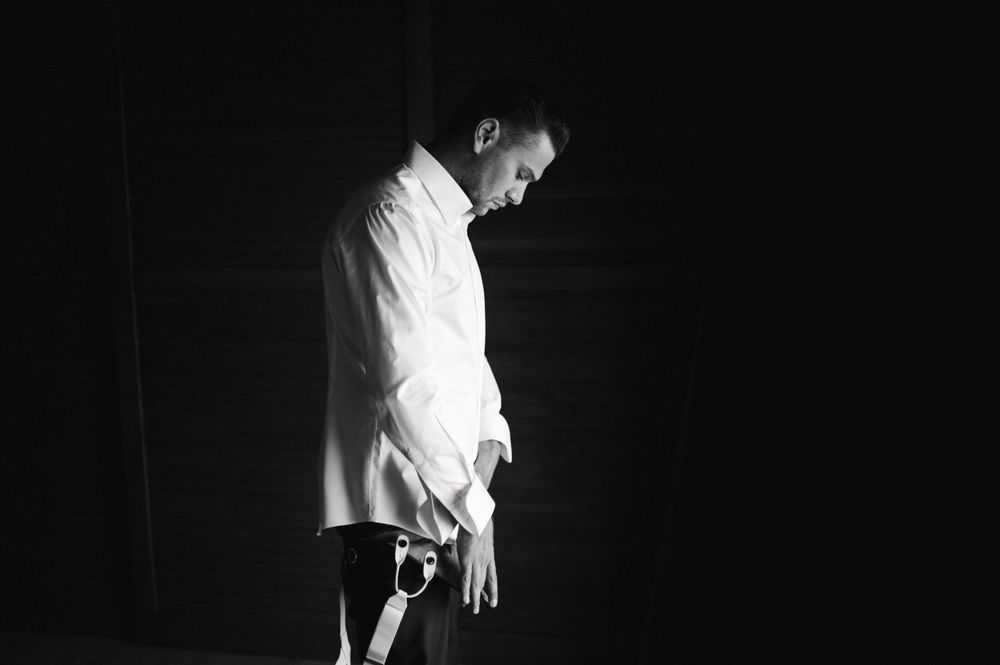 A figure in white clothing shown in dramatic black and white side lighting.