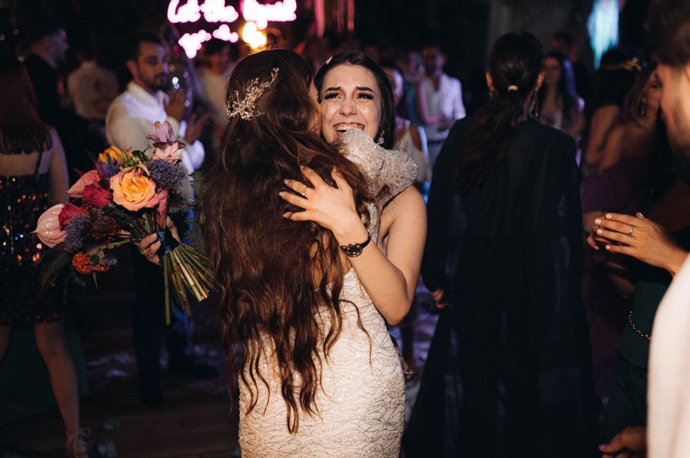 Emotional embrace shared during wedding reception celebration with floral bouquet.